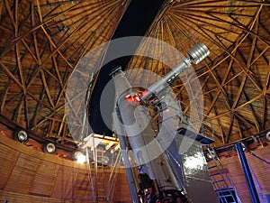 A telescope at Lowell Observatory with a view of Orion's belt and other stars visible in the sky out the window